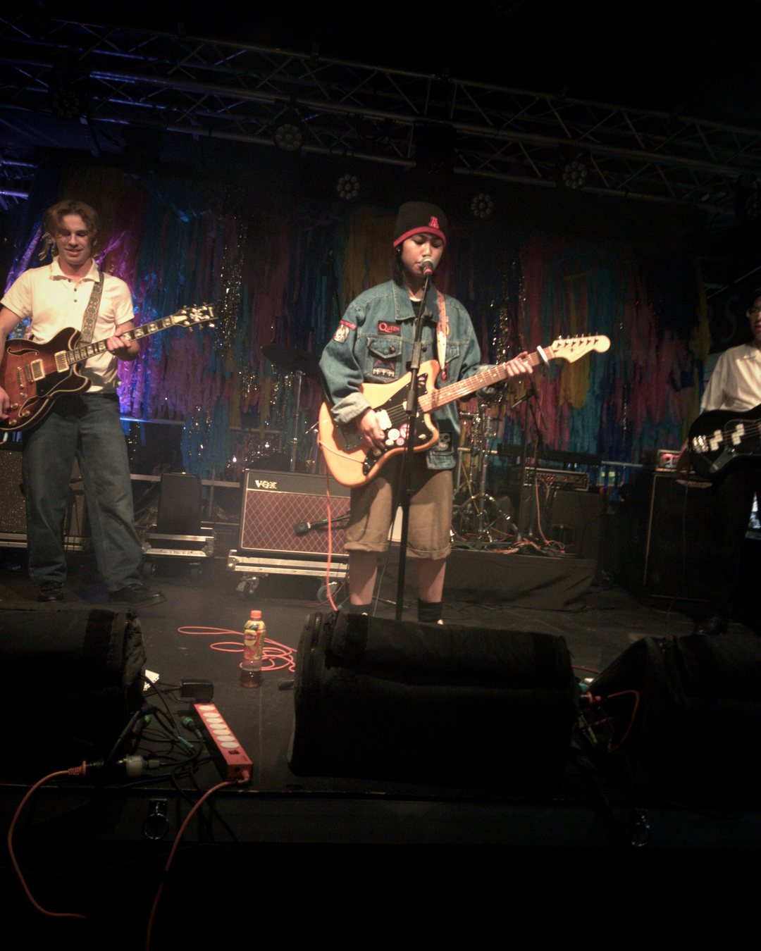 Ixara mid-set under stage lights, guitar up